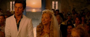 Movie still from “Mamma Mia!” (2008), directed by Phyllida Lloyd – A woman wearing a veil standing in front of a group of people; Close Up shot, Over the shoulder angle