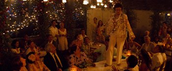 Movie still from “Mamma Mia!” (2008), directed by Phyllida Lloyd – A group of people sitting around a table with candles; Wide shot, Low angle