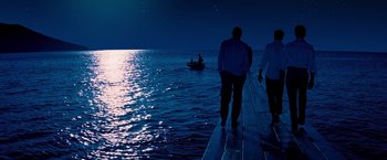 Movie still from “Mamma Mia!” (2008), directed by Phyllida Lloyd – Two people standing on a dock looking out at the water; Wide shot, High angle