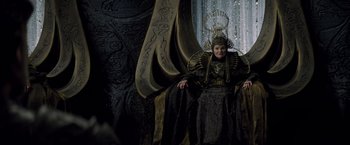 Movie still from “Man of Steel” (2013), directed by Zack Snyder – A woman sitting on top of a chair wearing a crown; Medium shot, Low angle