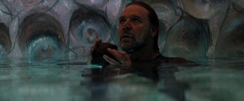 Movie still from “Man of Steel” (2013), directed by Zack Snyder – A man holding a piece of food in his hands while sitting in a pool; Close Up shot, Overhead angle