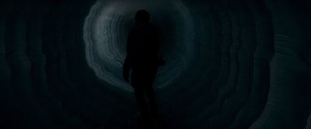 Movie still from “Man of Steel” (2013), directed by Zack Snyder – A person is standing in a dark tunnel; Wide shot, High angle