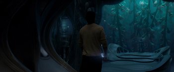 Movie still from “Man of Steel” (2013), directed by Zack Snyder – A man standing in front of an underwater scene; Wide shot, Over the shoulder angle