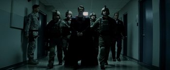 Movie still from “Man of Steel” (2013), directed by Zack Snyder – A group of men standing around a man in a black suit; Wide shot, Low angle
