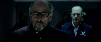 Movie still from “Man of Steel” (2013), directed by Zack Snyder – A man with a beard wearing glasses and a black shirt; Close Up shot, Low angle