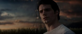 Movie still from “Man of Steel” (2013), directed by Zack Snyder – A person wearing a white t - shirt; Close Up shot, Over the shoulder angle