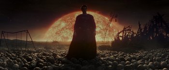 Movie still from “Man of Steel” (2013), directed by Zack Snyder – A man standing in the middle of a field with a red sun in the background; Wide shot, Low angle