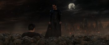 Movie still from “Man of Steel” (2013), directed by Zack Snyder – A man in a black suit standing in a field of skulls; Wide shot, Over the shoulder angle