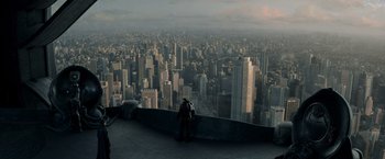 Movie still from “Man of Steel” (2013), directed by Zack Snyder – A man standing on the edge of a ledge looking at a city; Extreme Wide shot, High angle