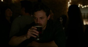 Movie still from “Manchester by the Sea” (2016), directed by Kenneth Lonergan – A man drinking a beer in a dark room; Close Up shot, Over the shoulder angle