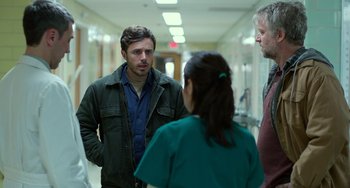 Movie still from “Manchester by the Sea” (2016), directed by Kenneth Lonergan – A group of people standing in a hospital hallway talking; Medium shot, Over the shoulder angle