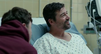 Movie still from “Manchester by the Sea” (2016), directed by Kenneth Lonergan – A man sitting in a hospital bed next to another man; Medium shot, Over the shoulder angle