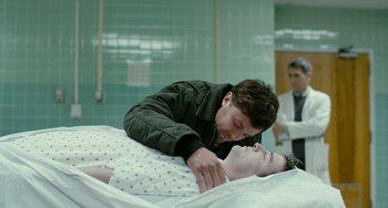 Movie still from “Manchester by the Sea” (2016), directed by Kenneth Lonergan – A man is laying on a woman in a hospital bed; Medium shot, Over the shoulder angle