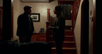 Movie still from “Manchester by the Sea” (2016), directed by Kenneth Lonergan – Two men are standing in a living room talking to each other; Medium shot, Over the shoulder angle