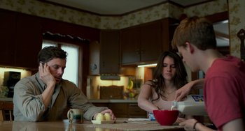 Movie still from “Manchester by the Sea” (2016), directed by Kenneth Lonergan – A group of people sitting at a table in a kitchen; Medium shot, Over the shoulder angle