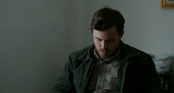 Movie still from “Manchester by the Sea” (2016), directed by Kenneth Lonergan – A man in a green jacket is looking down; Close Up shot, Over the shoulder angle