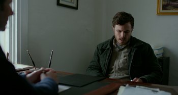 Movie still from “Manchester by the Sea” (2016), directed by Kenneth Lonergan – A man sitting at a table in front of another man; Medium shot, Over the shoulder angle