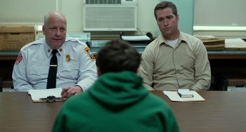 Movie still from “Manchester by the Sea” (2016), directed by Kenneth Lonergan – Two police officers sitting at a table with a man in front of them; Medium shot, Over the shoulder angle