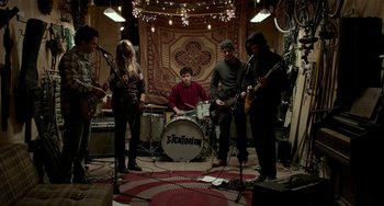 Movie still from “Manchester by the Sea” (2016), directed by Kenneth Lonergan – A group of people playing instruments in a room; Wide shot, Over the shoulder angle