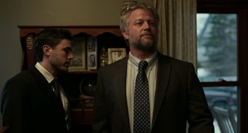 Movie still from “Manchester by the Sea” (2016), directed by Kenneth Lonergan – A man in a suit standing next to another man in a suit; Close Up shot, Low angle