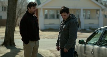Movie still from “Manchester by the Sea” (2016), directed by Kenneth Lonergan – Two men standing next to each other near a car; Medium shot, Over the shoulder angle