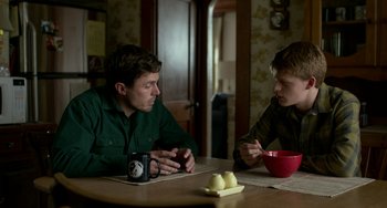 Movie still from “Manchester by the Sea” (2016), directed by Kenneth Lonergan – Two young men sitting at a table with a bowl of fruit; Medium shot, Over the shoulder angle