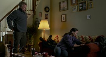 Movie still from “Manchester by the Sea” (2016), directed by Kenneth Lonergan – A woman sitting on a couch in a living room; Medium shot, High angle