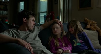 Movie still from “Manchester by the Sea” (2016), directed by Kenneth Lonergan – A man and two young girls sitting on a couch; Medium shot, Over the shoulder angle