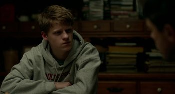 Movie still from “Manchester by the Sea” (2016), directed by Kenneth Lonergan – A young man sitting in front of a bookshelf; Close Up shot, Over the shoulder angle