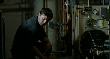 Movie still from “Manchester by the Sea” (2016), directed by Kenneth Lonergan – A man in black shirt fixing pipes inside of a building; Medium shot, Low angle
