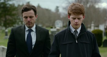 Movie still from “Manchester by the Sea” (2016), directed by Kenneth Lonergan – Two men in business suits standing next to each other in a cemetery; Close Up shot, Over the shoulder angle