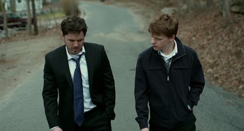 Movie still from “Manchester by the Sea” (2016), directed by Kenneth Lonergan – Two men in business suits walking down a road; Medium shot, Over the shoulder angle