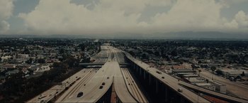 Movie still from “Manifest West” (2022), directed by Joe Dietsch – An aerial view of an interstate highway in the middle of the day; Extreme Wide shot, High angle