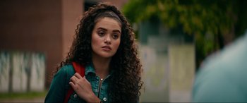 Movie still from “Margaux” (2022), directed by Steven C. Miller – A woman with long curly hair holding a red bag; Close Up shot, Over the shoulder angle