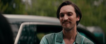 Movie still from “Margaux” (2022), directed by Steven C. Miller – A person with long hair and a beard; Close Up shot, Over the shoulder angle