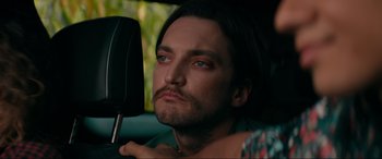 Movie still from “Margaux” (2022), directed by Steven C. Miller – A man sitting in the driver's seat of a car looking into a mirror; Close Up shot, Over the shoulder angle