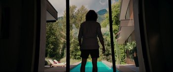Movie still from “Margaux” (2022), directed by Steven C. Miller – A woman standing in front of a window looking out at the mountains; Wide shot, Low angle