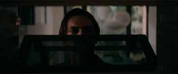 Movie still from “Margaux” (2022), directed by Steven C. Miller – A man looking through the blinds of a window at night; Close Up shot, Low angle