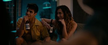 Movie still from “Margaux” (2022), directed by Steven C. Miller – A woman sitting at a table holding a bottle of beer; Medium shot, Over the shoulder angle