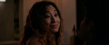 Movie still from “Margaux” (2022), directed by Steven C. Miller – A person with curly hair smiling; Close Up shot, Over the shoulder angle