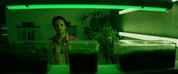 Movie still from “Margaux” (2022), directed by Steven C. Miller – A man is standing in front of some plants; Medium shot, Low angle