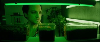 Movie still from “Margaux” (2022), directed by Steven C. Miller – A man sitting in front of a green light; Close Up shot, Low angle