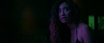 Movie still from “Margaux” (2022), directed by Steven C. Miller – A woman with long curly black hair wearing headphones; Close Up shot, Over the shoulder angle