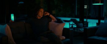 Movie still from “Margaux” (2022), directed by Steven C. Miller – A man sitting on a couch in a dark room; Medium shot, Over the shoulder angle