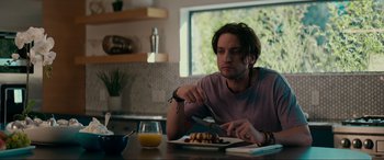 Movie still from “Margaux” (2022), directed by Steven C. Miller – A man sitting at a table with a plate of food; Medium shot, Low angle