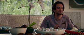 Movie still from “Margaux” (2022), directed by Steven C. Miller – A man sitting in front of a bowl of fruit; Medium shot, Over the shoulder angle