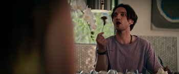 Movie still from “Margaux” (2022), directed by Steven C. Miller – A man holding a chocolate bar in front of a glass of wine; Close Up shot, Over the shoulder angle