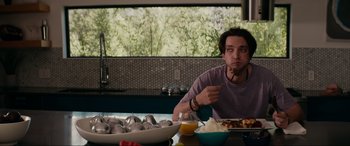 Movie still from “Margaux” (2022), directed by Steven C. Miller – A man sitting at a table with a bowl of food; Medium shot, Over the shoulder angle