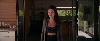 Movie still from “Margaux” (2022), directed by Steven C. Miller – A woman with curly brown hair wearing a black top; Medium shot, Over the shoulder angle