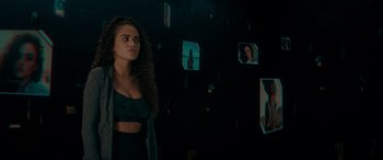 Movie still from “Margaux” (2022), directed by Steven C. Miller – A woman standing next to a wall with pictures on the wall; Medium shot, Low angle